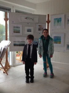 Saras children standing in front of her displayed artwork